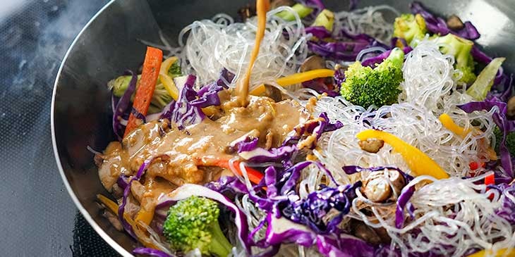 adding-sauce-to-vegan-pad-thai-in-wok