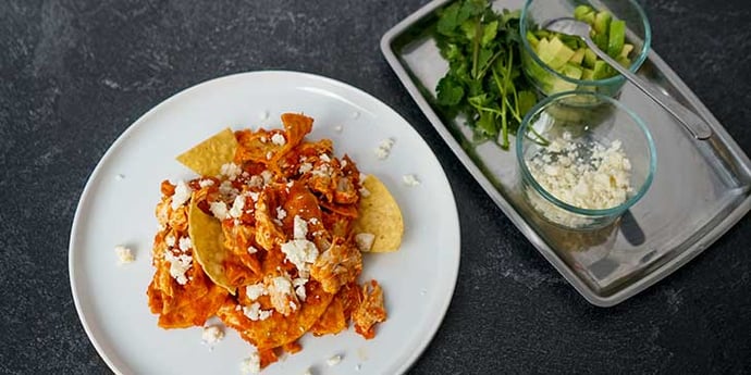 Chilaquiles Chicken Recipe plated on a white porcelain plate with garnishes on the side