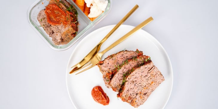 Gluten Free Paleo Meatloaf Recipe plated on a white round plate and meal prep container next to golden silverware