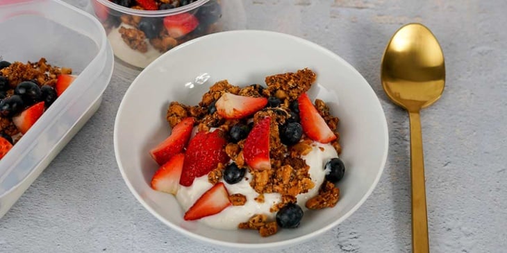 Paleo coconut yogurt parfait recipe plated on a white bowl with colorful berries and a golden spoon on the side
